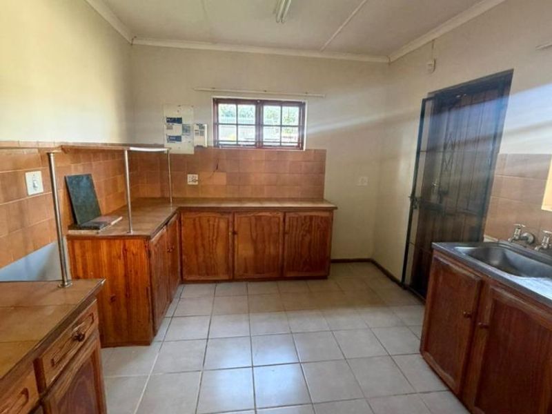 A functional kitchen featuring wooden cabinetry, tiled countertops, and tiled flooring, offering a blank canvas for potential modernization and renovation.