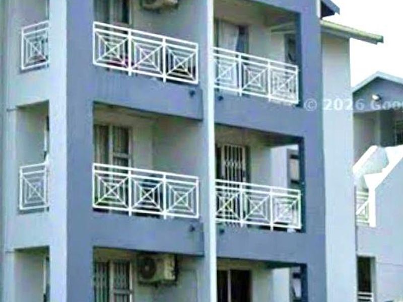 Exterior view of a multi-story apartment building featuring private balconies with white railings and mounted air conditioning units.