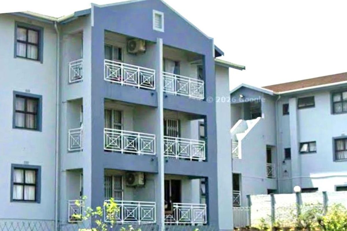Exterior view of a multi-story apartment building featuring private balconies with metal railings and external air conditioning units.