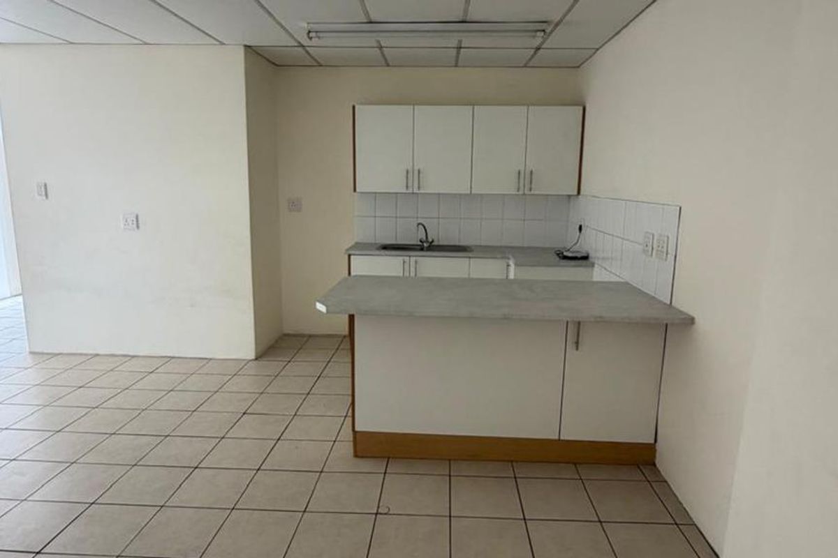 An empty kitchen featuring tiled flooring, built-in cabinetry with laminate countertops, and a tiled backsplash, offering a blank canvas for renovation.