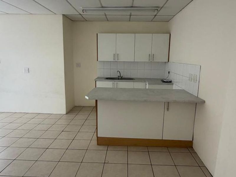 An empty kitchen featuring tiled flooring, built-in cabinetry with laminate countertops, and a tiled backsplash, offering a blank canvas for renovation.