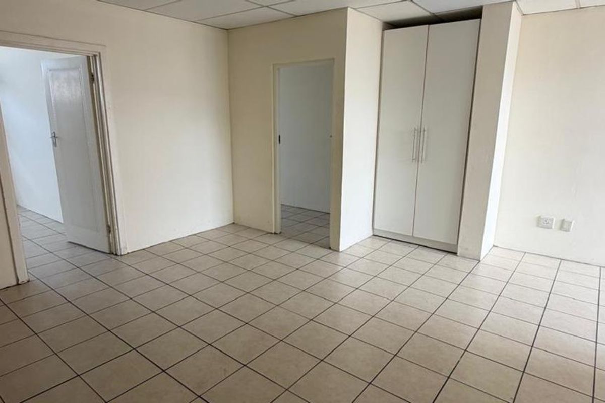 An empty bedroom featuring tiled flooring, a built-in wardrobe, and a drop ceiling, offering a blank canvas for renovation or interior design.