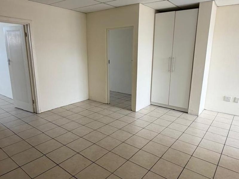 An empty bedroom featuring tiled flooring, a built-in wardrobe, and a drop ceiling, offering a blank canvas for renovation or interior design.