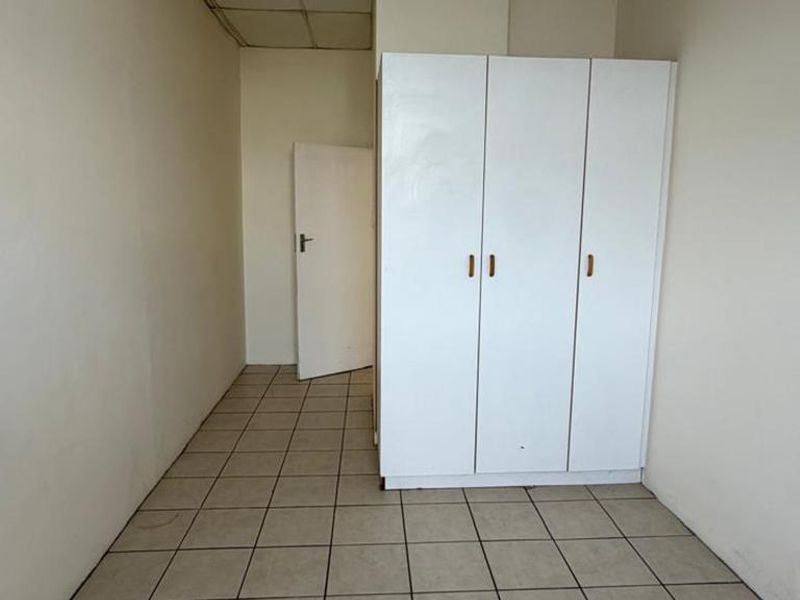 A vacant bedroom featuring tiled flooring, a built-in wardrobe, and a drop ceiling, offering a blank canvas for renovation.
