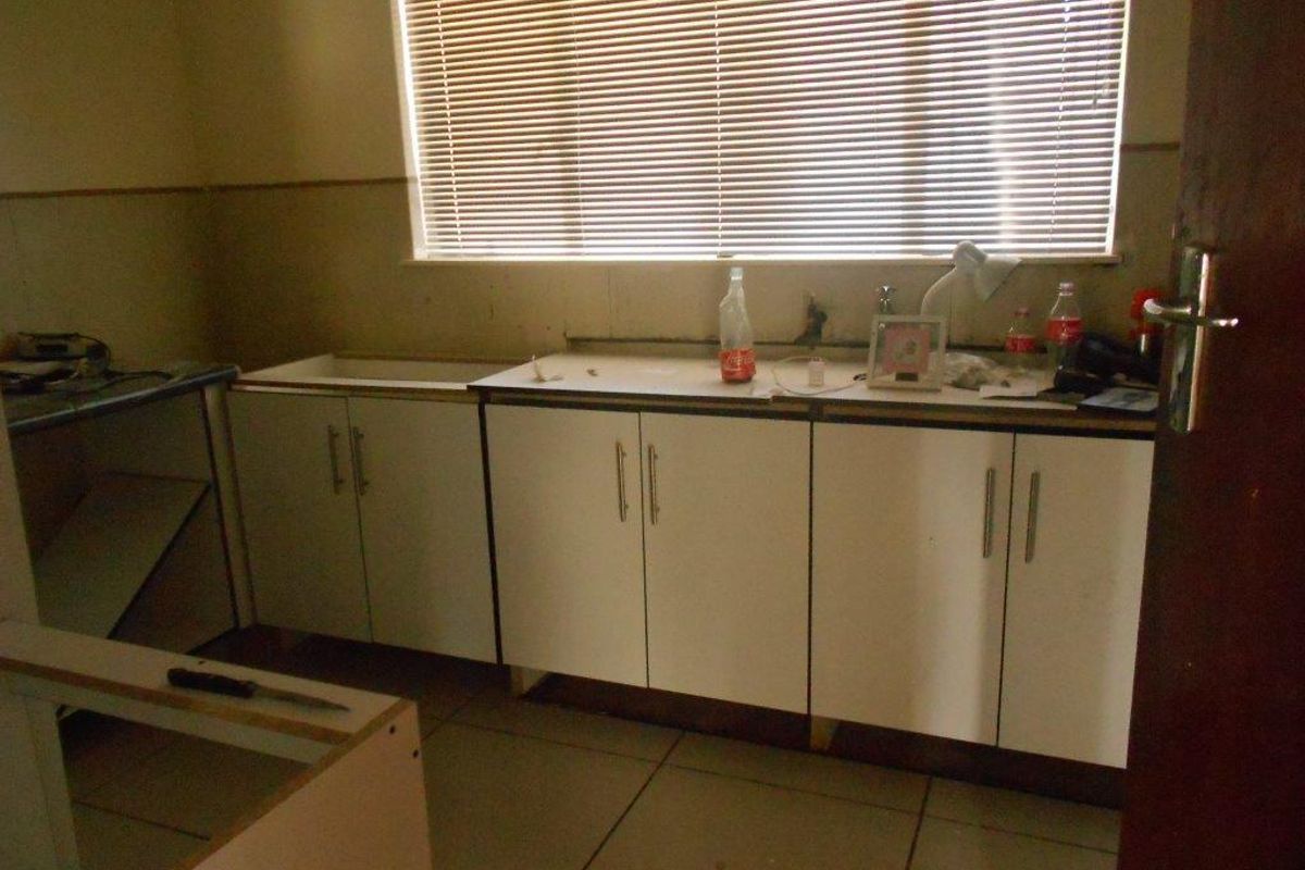 A dated kitchen space featuring built-in cabinetry and tiled flooring, currently requiring significant renovation and completion of fixtures.