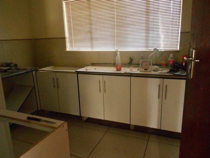 A dated kitchen space featuring built-in cabinetry and tiled flooring, currently requiring significant renovation and completion of fixtures.