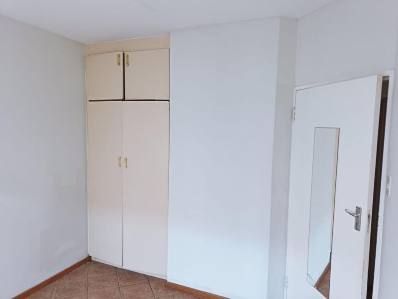 A vacant bedroom featuring built-in cupboards, tiled flooring, and a standard internal door, offering a blank canvas for potential updates.