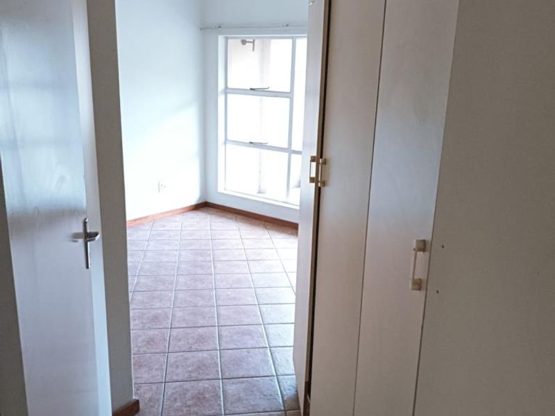 An empty bedroom featuring tiled flooring and built-in cupboards, offering a neutral space ready for personalization.
