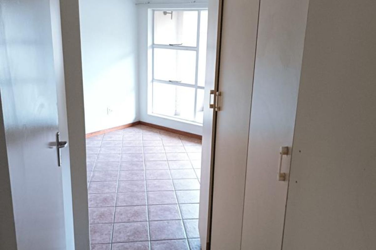 An empty bedroom featuring tiled flooring and built-in cupboards, offering a neutral space ready for personalization.