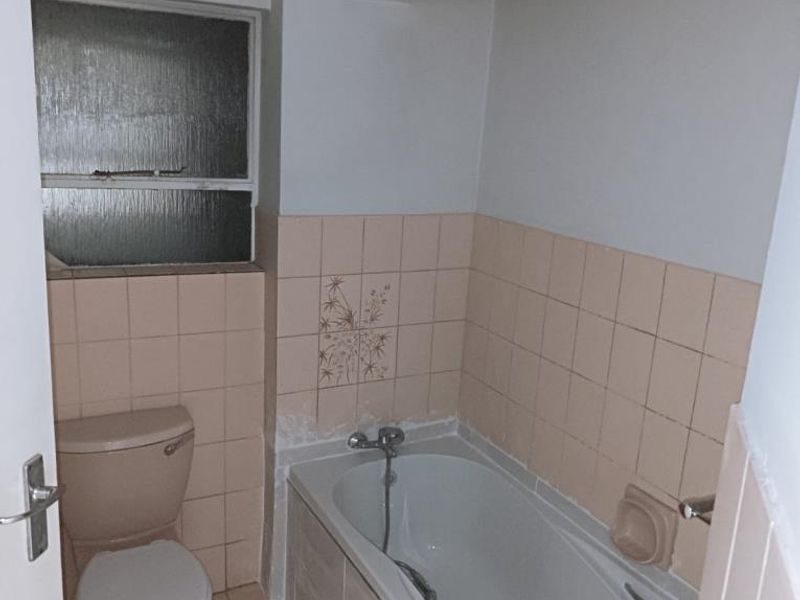 A dated bathroom featuring a standard bathtub, toilet, and original wall tiling, offering potential for a modern renovation.