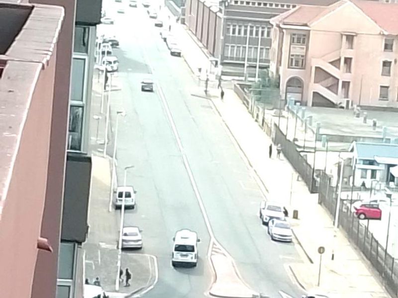 An elevated street view looking down onto a city road with a roundabout and surrounding urban buildings.