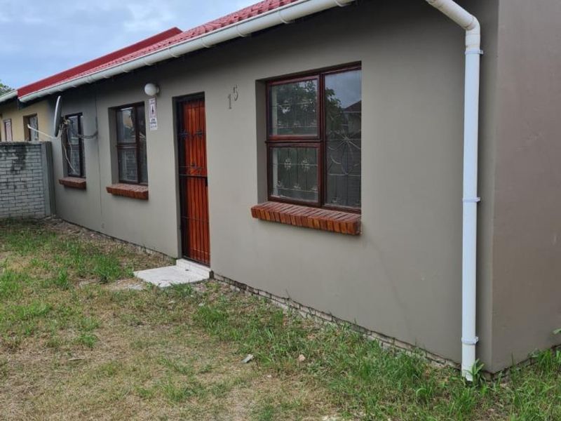 A view of the front facade of a single-story house featuring a tiled roof, security gate, and metal-framed windows with security bars.