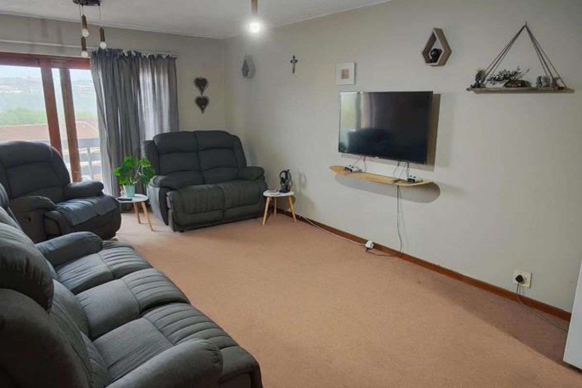 A spacious living room featuring carpeted flooring and a large sliding glass door that provides natural light and access to the exterior.