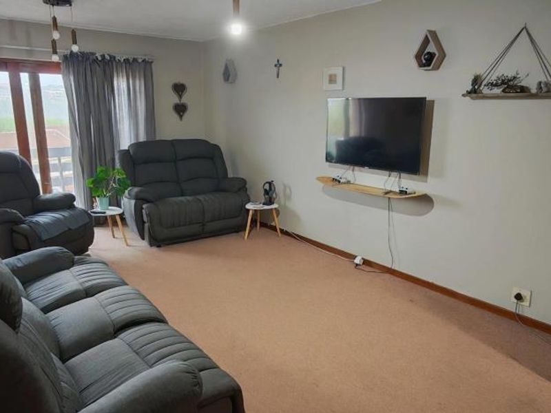 A spacious living room featuring carpeted flooring and a large sliding glass door that provides natural light and access to the exterior.