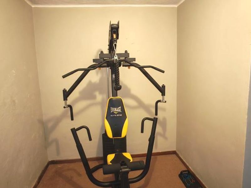 A small dedicated gym space with neutral walls and carpeted flooring, suitable for a home fitness setup.