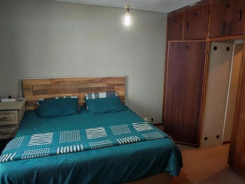 A bedroom featuring extensive built-in wooden cabinetry providing ample storage space, with neutral wall finishes and natural light from the window.