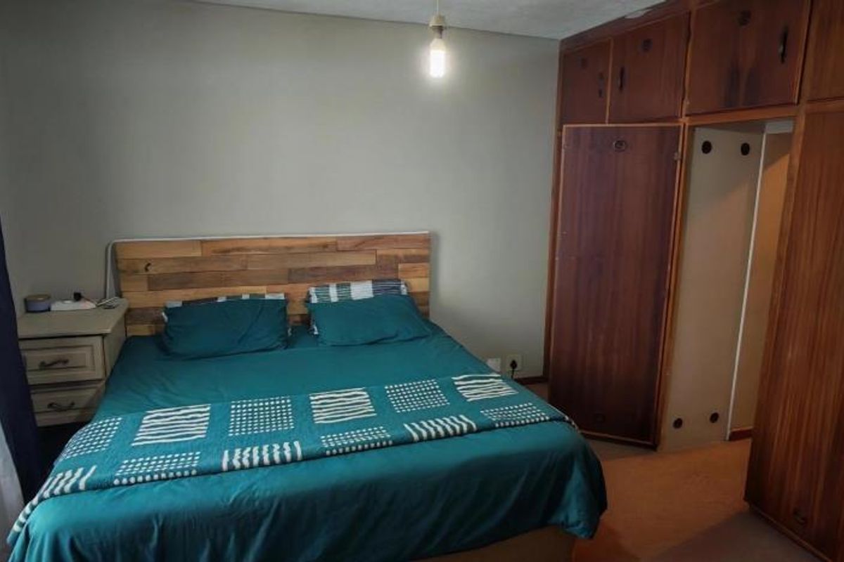 A bedroom featuring extensive built-in wooden cabinetry providing ample storage space, with neutral wall finishes and natural light from the window.