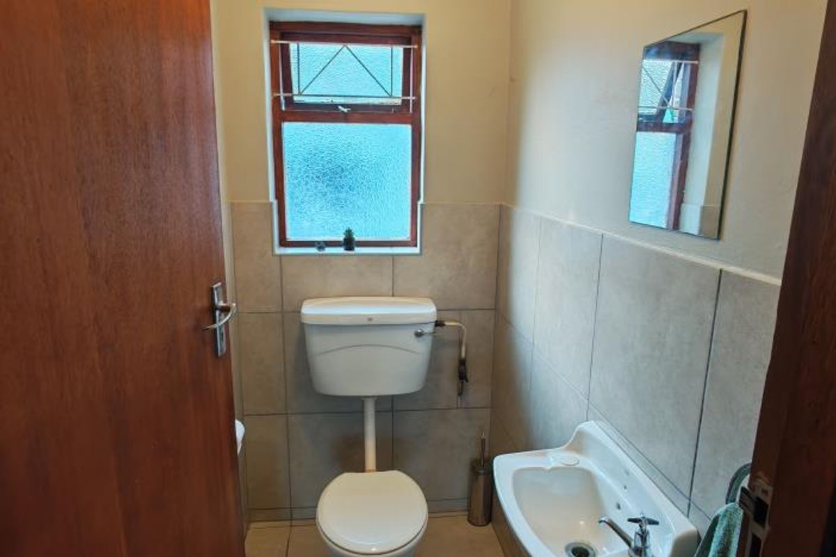 A compact guest bathroom featuring tiled walls, a wall-mounted basin, and a standard toilet.