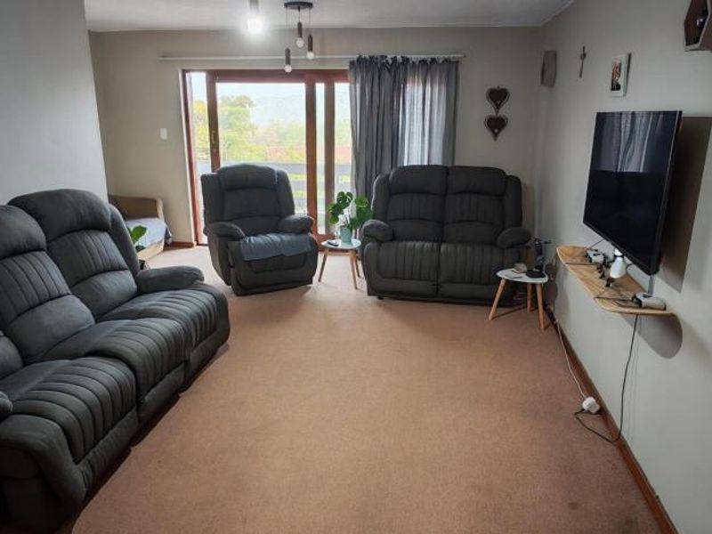 A comfortable living room featuring carpeted flooring and a large sliding glass door that provides natural light and access to the outdoors.