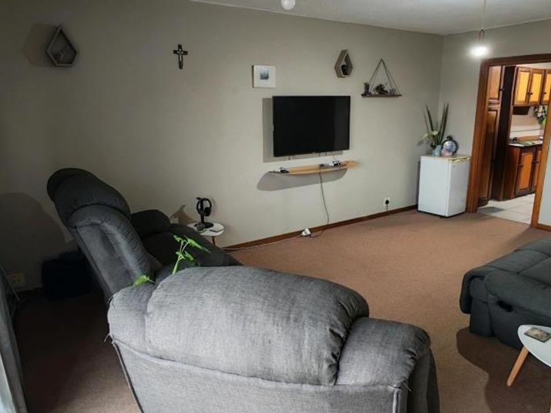 A comfortable living room featuring carpeted flooring and access to an outdoor area through a sliding door.