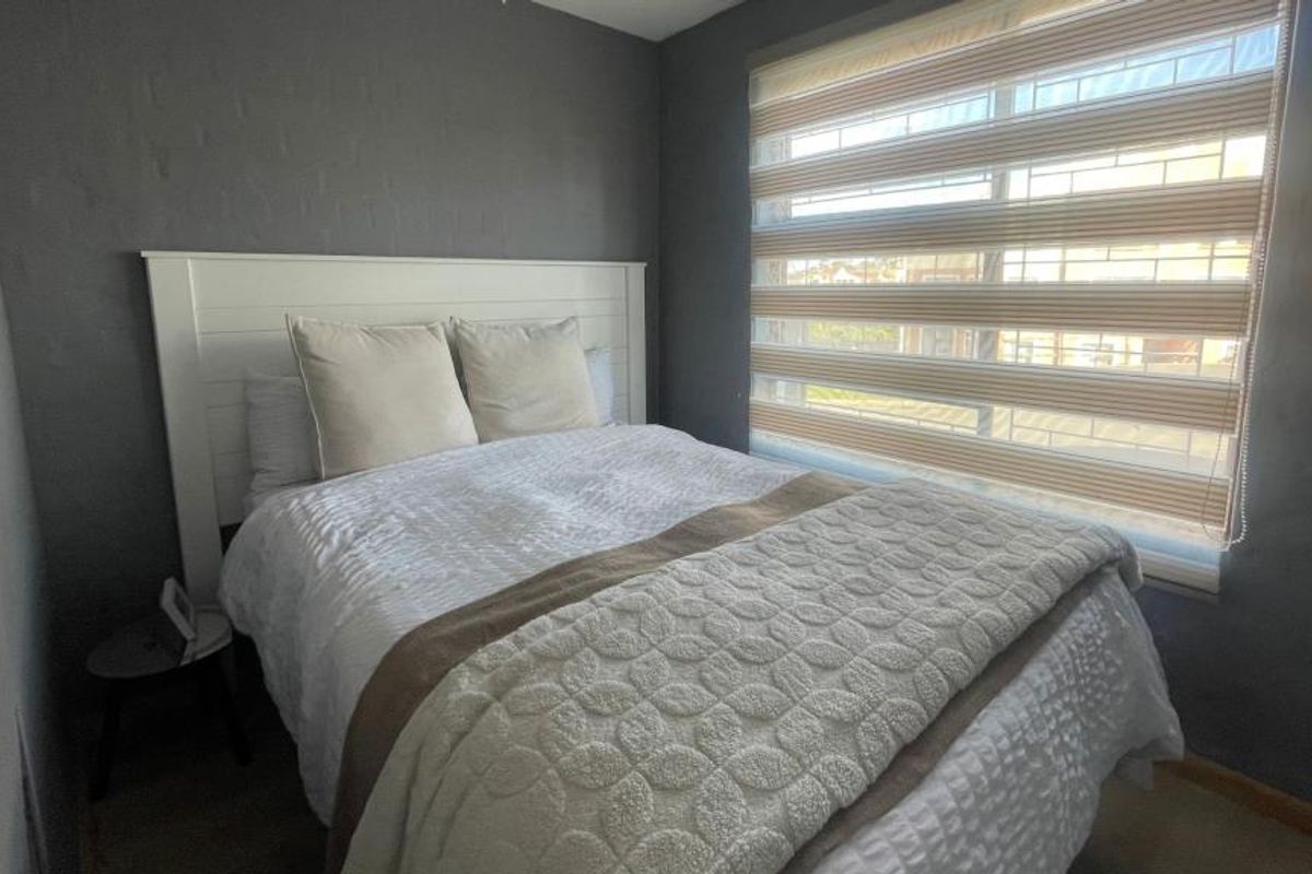 A cozy bedroom featuring dark painted walls and modern window blinds, providing a comfortable and private sleeping space.