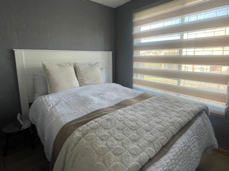 A cozy bedroom featuring dark painted walls and modern window blinds, providing a comfortable and private sleeping space.