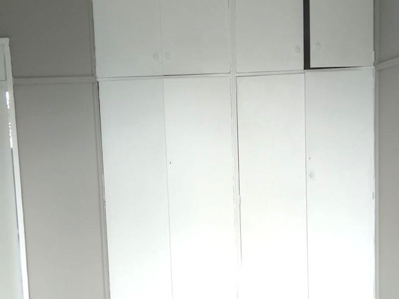 A bedroom featuring built-in cupboards with overhead storage and tiled flooring.