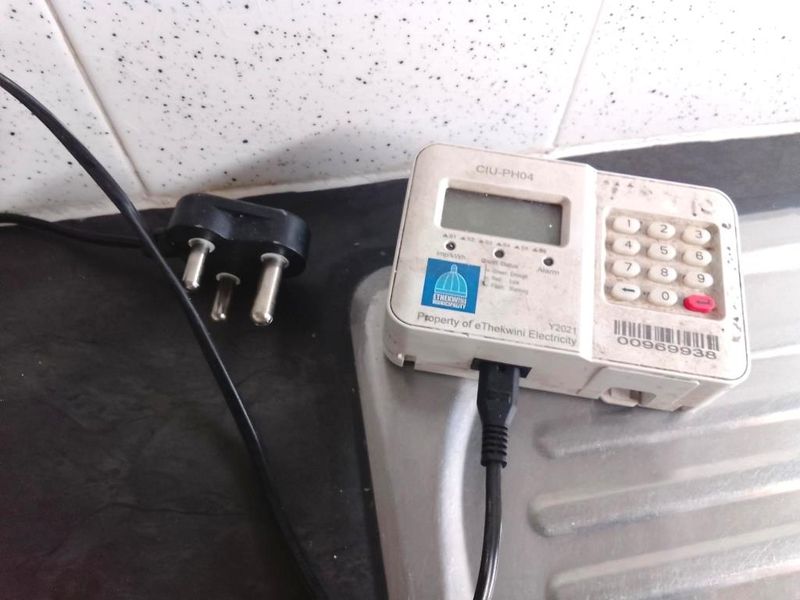 Close-up view of a prepaid electricity meter unit mounted on a kitchen countertop against a tiled backsplash.