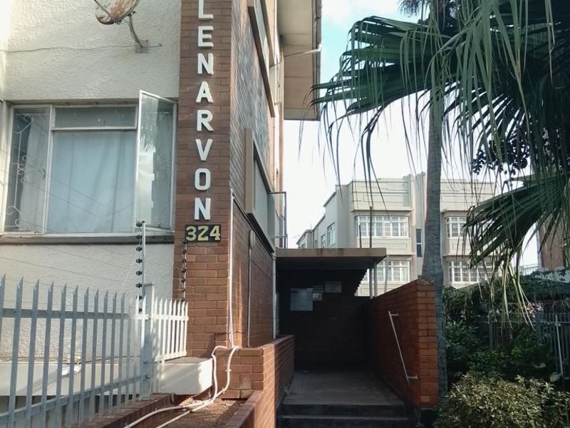Front entrance view of the Clenarvon apartment building, featuring brick facade, security fencing, and concrete access stairs.