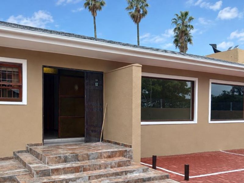 Front elevation of the house featuring a paved driveway, tiled entrance steps, and secure aluminium-framed windows.