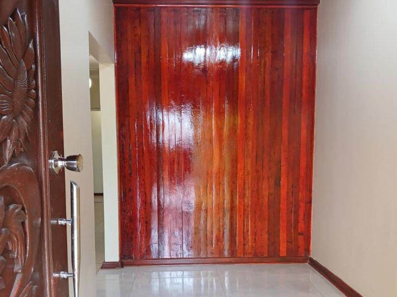 Entrance foyer featuring a decorative carved wooden front door, polished timber feature wall paneling, and clean tiled flooring.