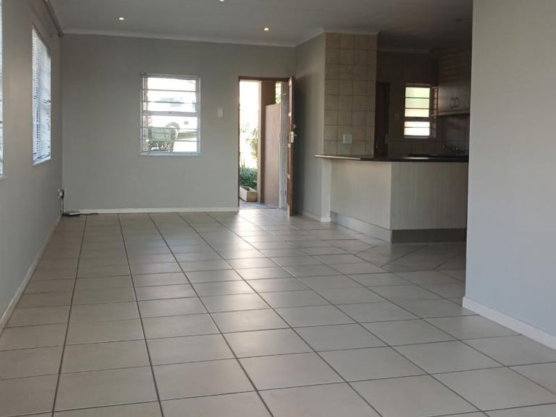 Spacious open-plan living and kitchen area featuring neutral tiled flooring, recessed lighting, and a functional breakfast bar layout.