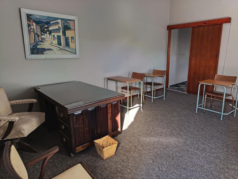 A functional office space featuring carpeted flooring and a sliding wooden door, suitable for a professional work environment.