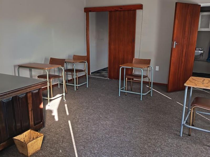 A functional office space featuring carpeted flooring, a sliding wooden door, and neutral wall finishes, suitable for a professional work environment.