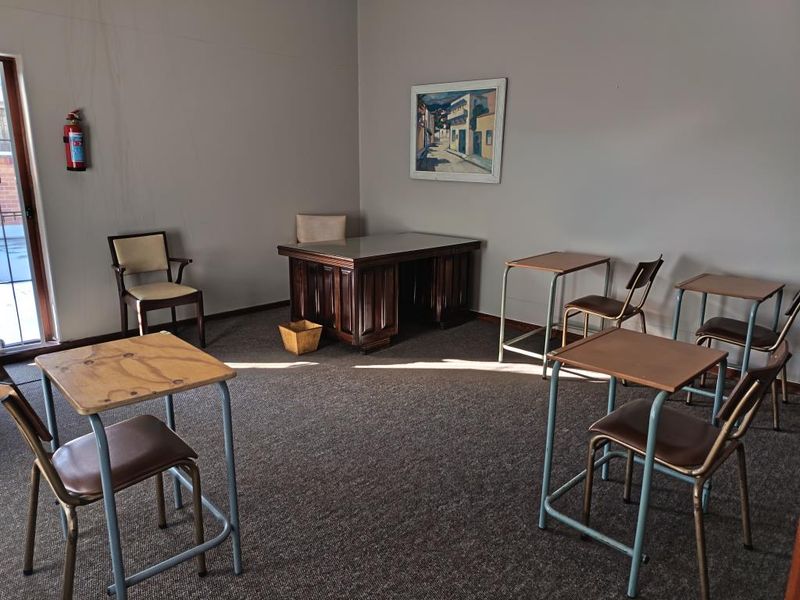 A functional commercial office space featuring carpeted flooring, a sliding glass door for natural light, and a wall-mounted fire extinguisher.
