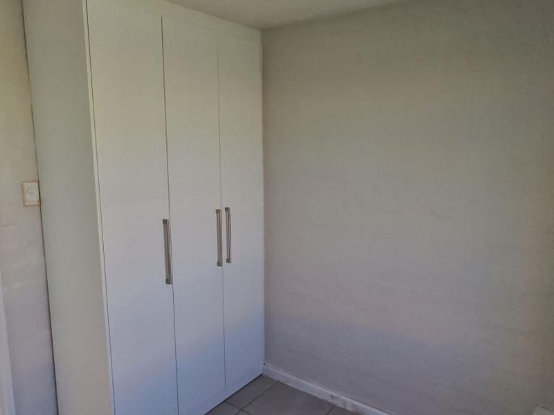 A clean, empty bedroom featuring a white built-in wardrobe and neutral tiled flooring, offering a blank canvas for personalization.