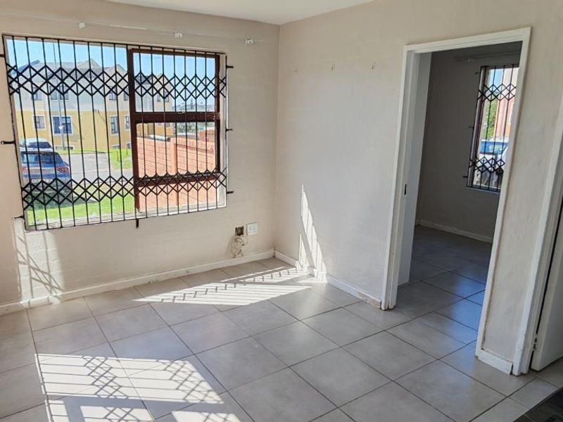 An empty living area featuring tiled flooring and security bars on the windows, offering a blank canvas for interior design.