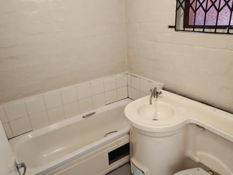 A dated bathroom featuring an integrated vanity and bathtub unit, requiring modernization of fixtures and finishes to improve functionality and aesthetic appeal.