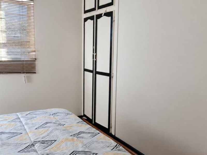 A bedroom featuring a built-in wardrobe with contrasting trim and venetian blinds on the window.