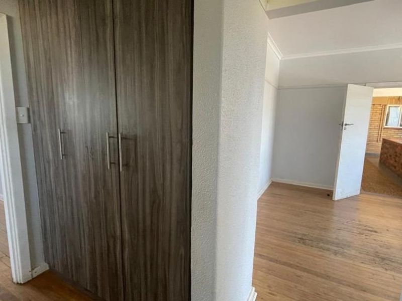 A bright hallway featuring timber flooring and a modern built-in cupboard, providing access to adjacent living spaces.