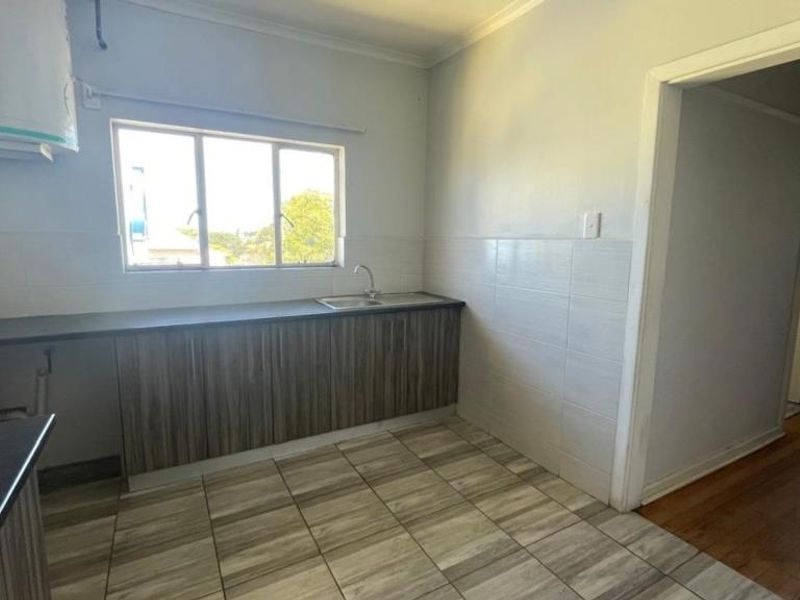 A functional kitchen featuring built-in cabinetry, laminate countertops, a stainless steel sink, and tiled flooring, offering a clean and practical workspace.
