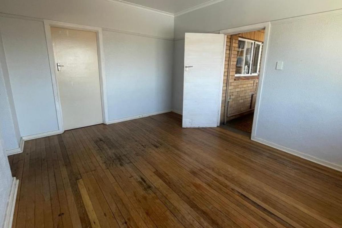 An empty bedroom featuring original hardwood flooring and neutral wall finishes, providing a blank canvas for renovation or interior design updates.