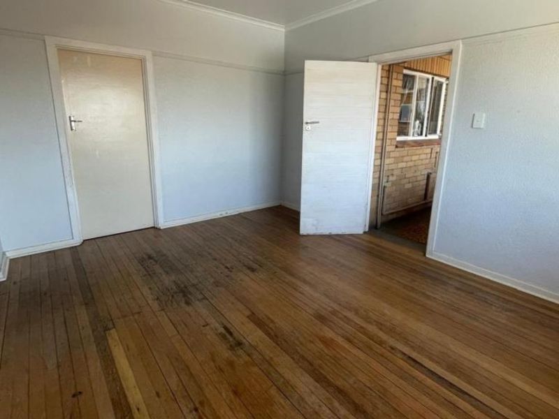 An empty bedroom featuring original hardwood flooring and neutral wall finishes, providing a blank canvas for renovation or interior design updates.