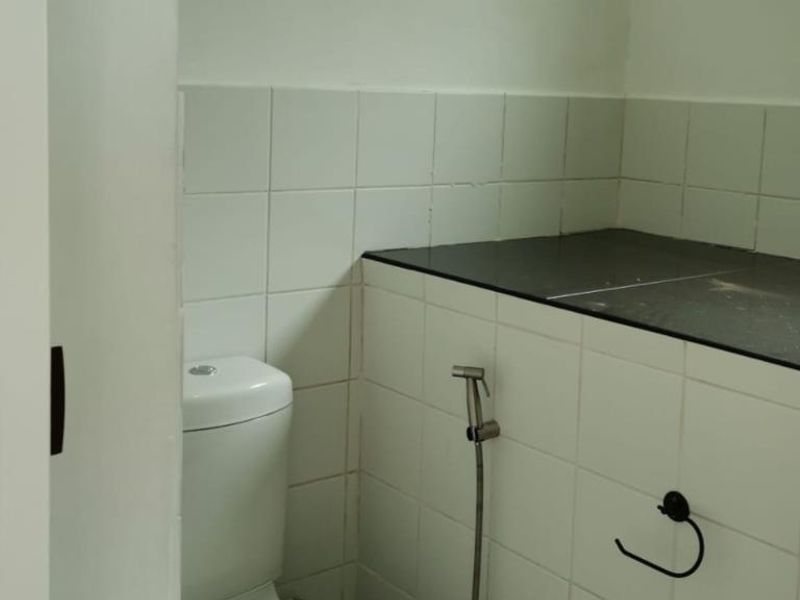 A small bathroom featuring tiled walls, a toilet, and a stone countertop, currently requiring completion of plumbing fixtures.