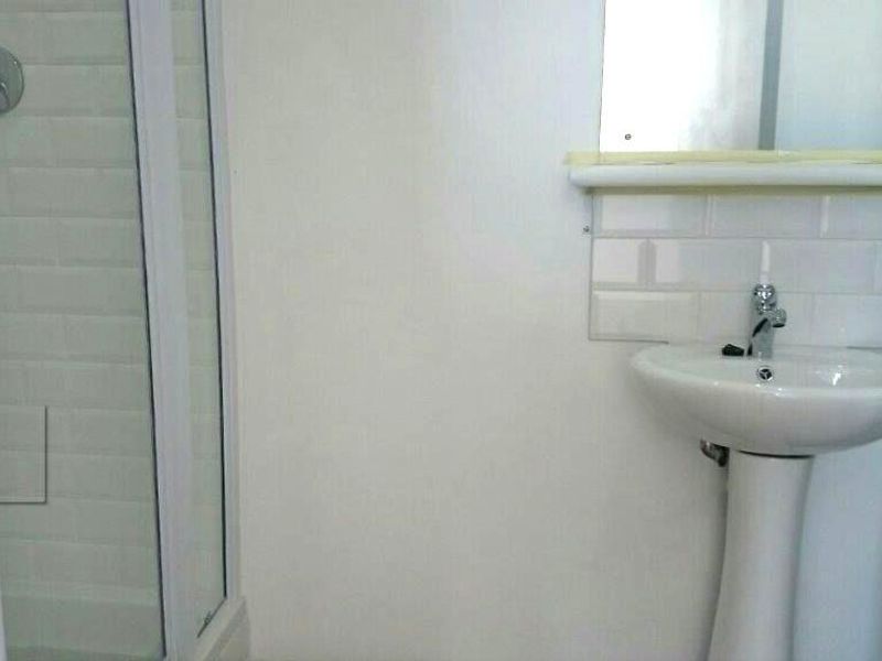 A compact bathroom featuring a pedestal basin with subway tile splashback and a separate shower enclosure.