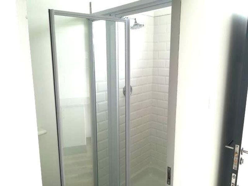 A clean, modern shower stall featuring white subway tile wall cladding and a glass enclosure.