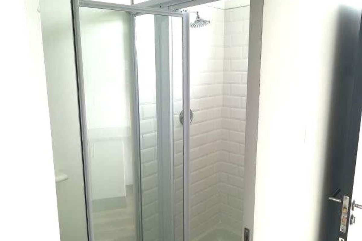 A clean, modern shower stall featuring white subway tile wall cladding and a glass enclosure.