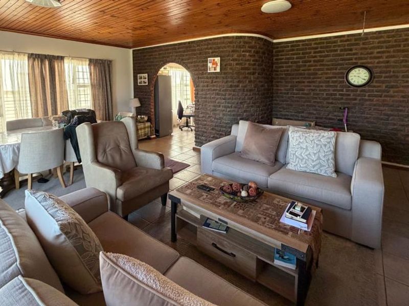 Spacious open-plan living and dining area featuring a distinctive exposed brick feature wall and warm timber tongue and groove ceiling.