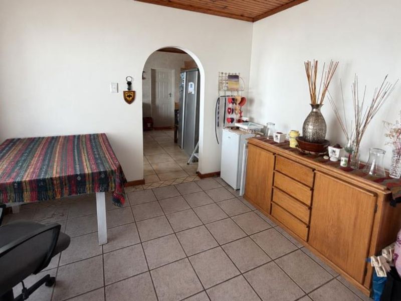 Dining area featuring tiled flooring and a timber ceiling, with an arched doorway leading to the kitchen area.
