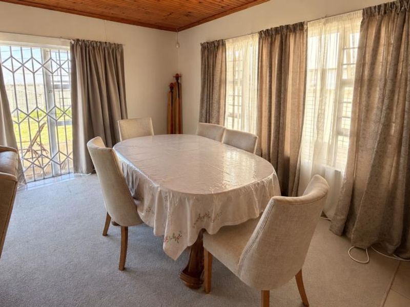 Dining room featuring a timber ceiling, large windows for natural light, and a security gate providing access to the exterior.